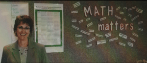 Sharon Carroll posing in classroom next to bulletin board titled "Math Matters"